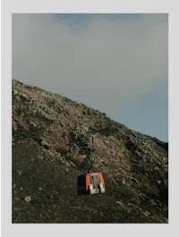 a small red building sitting on top of a rocky hill